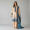 A woman models a traditional three-piece salwar kameez suit set. The set features a beige tunic (kameez) with blue floral embroidery and a blue border, matching beige trousers, and a coordinating blue dupatta with a blue-to-black gradient floral print.
